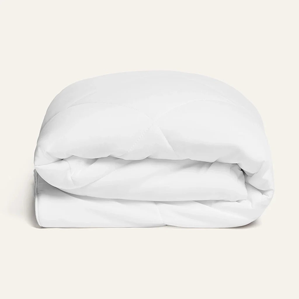 Folded white comforter on a light beige background